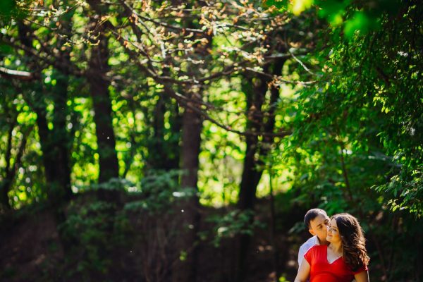 husband-with-pregnant-wife-embracing-forest-min